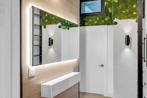 Une salle de bain moderne avec un grand miroir, un banc intégré et un luminaire fixé au mur.