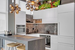 Une cuisine moderne dotée d’un îlot central, d’un four encastré et d’un crédence décorative.