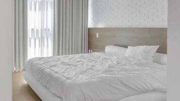 A modern bedroom with a large bed, white bedding, and a brick-patterned wall.