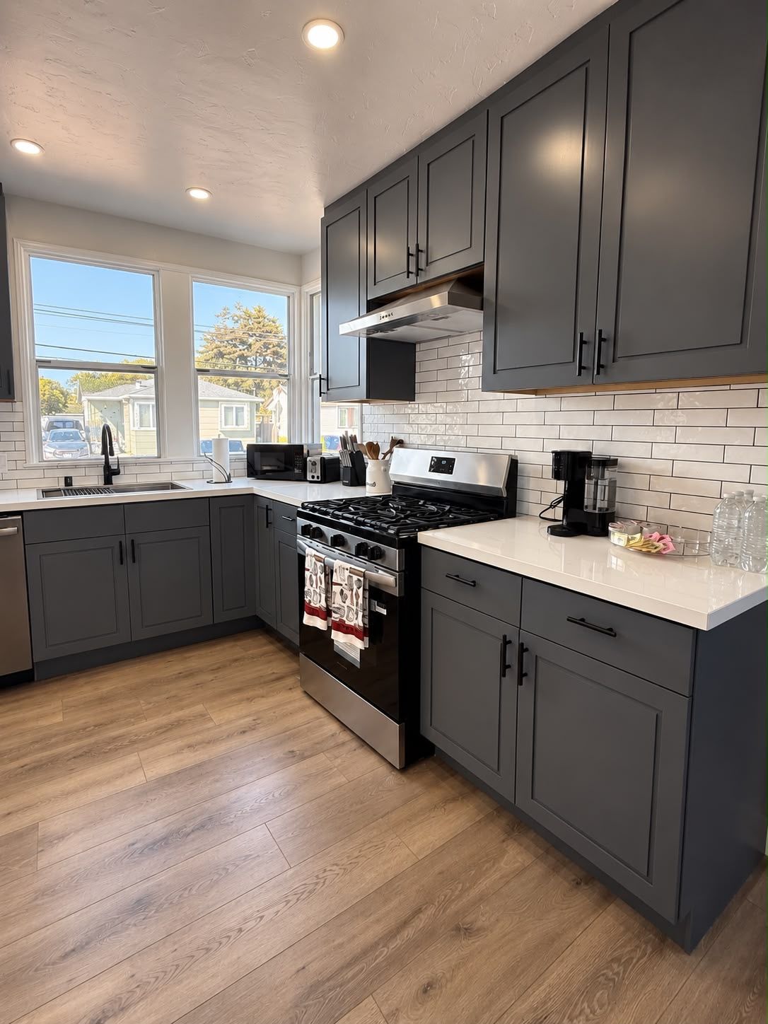 A modern kitchen with grey cabinets, a stainless steel stove, and a white countertop.
