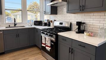 A modern kitchen with grey cabinets, a stainless steel stove, and a white countertop.