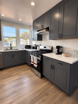 A modern kitchen with grey cabinets, a stainless steel stove, and a white countertop.