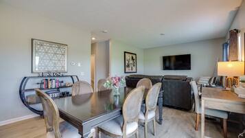 A dining area with a large table, chairs, and a bookshelf.