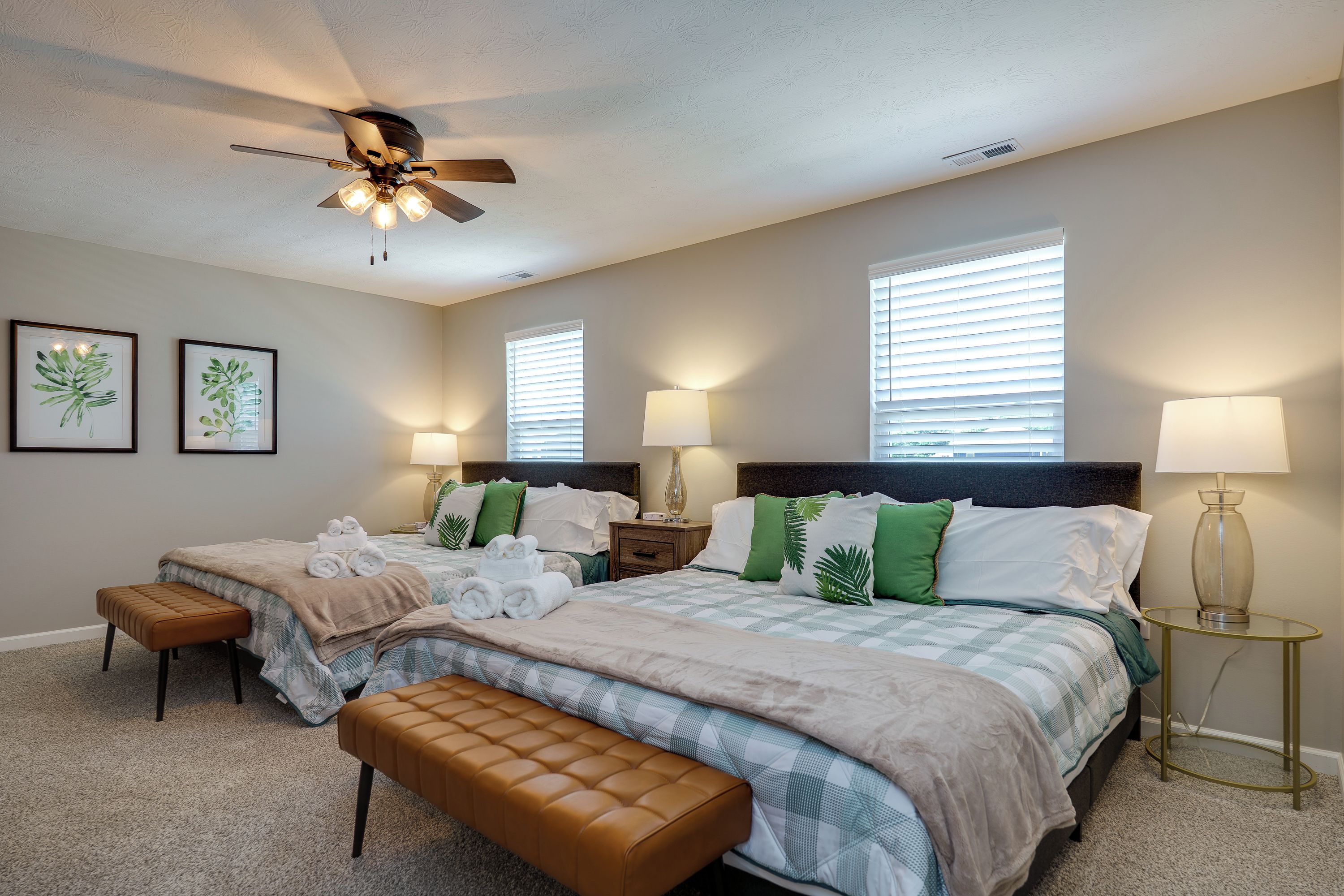 A bedroom with two beds, a ceiling fan, and two bedside lamps.