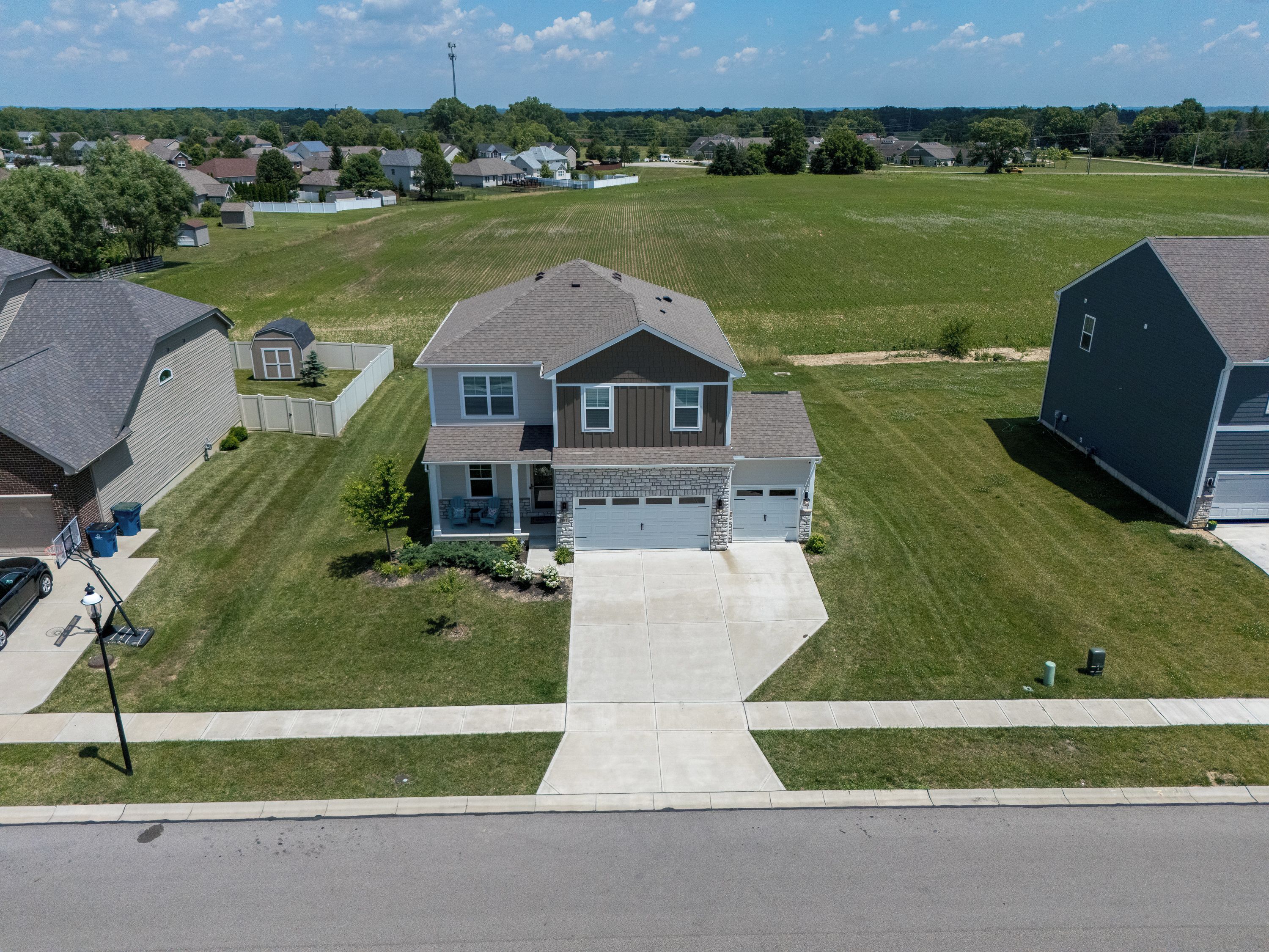 A residential area with a two-story house featuring a front porch, garage, and a well-maintained lawn.