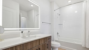 A modern bathroom with a large mirror, a sink, a toilet, and a shower area. - Modern 1BR Apartment near PGA and Universal Studios (Frisco)