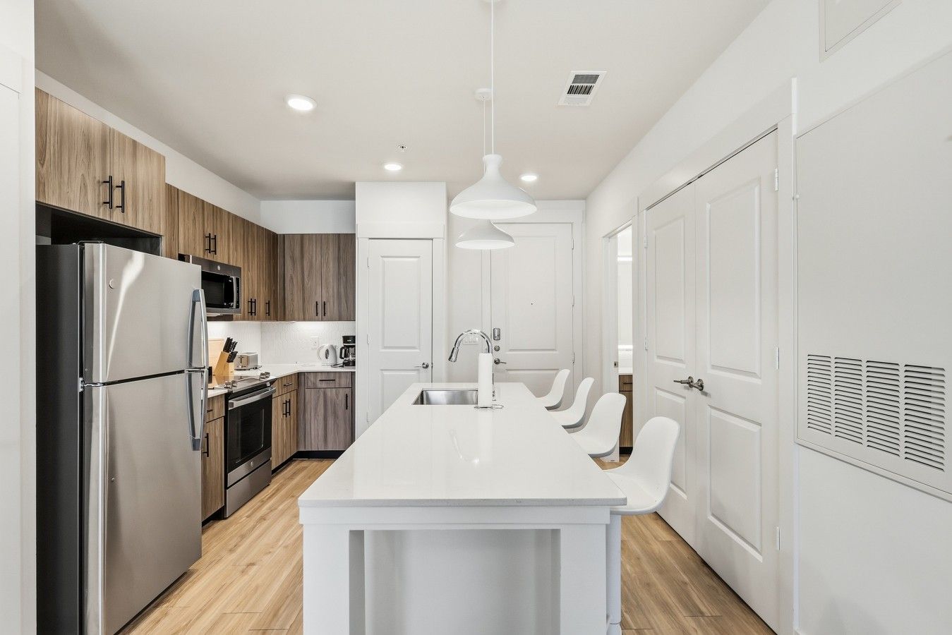Una cocina moderna con una isla central, electrodomésticos de acero inoxidable y muebles de madera.