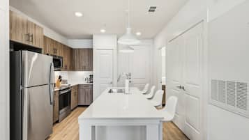 Una cocina moderna con una isla central, electrodomésticos de acero inoxidable y muebles de madera.