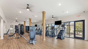 A gym with cardio machines, weight training equipment, and large windows. - Modern 1BR Apartment near PGA and Universal Studios (Frisco)