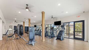 A gym with cardio machines, weight training equipment, and large windows.