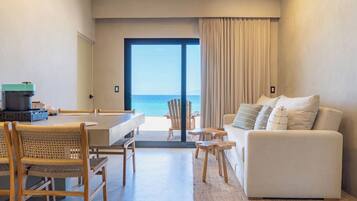 Un salón moderno con vista al mar, un comedor con mesa y sillas, y un sofá con cojines.