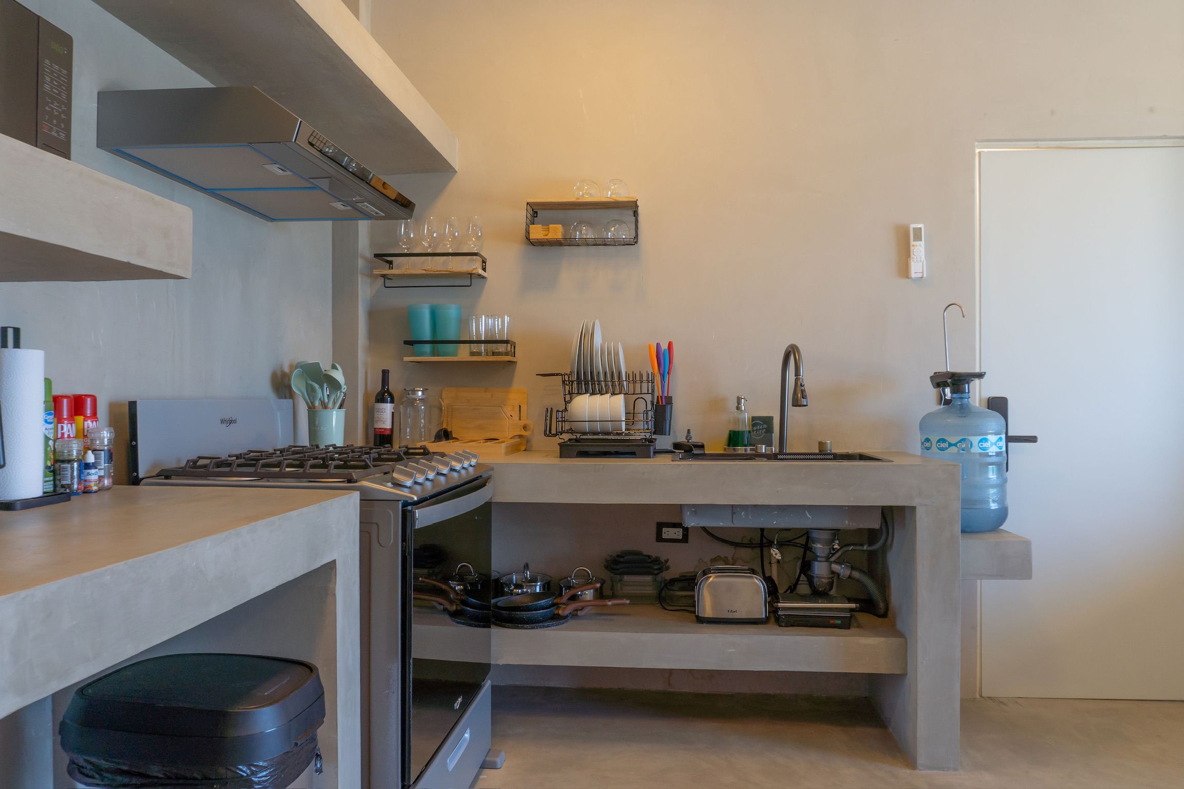 Una cocina compacta con estufa integrada, un lavamanos y dispensador de agua.