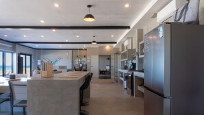 Une cuisine moderne dotée d’un îlot central, d’appareils électroménagers en acier inoxydable et offrant une vue sur l’extérieur.