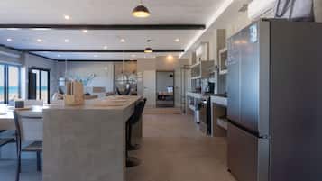 A modern kitchen with a central island, stainless steel appliances, and a view to the outside.