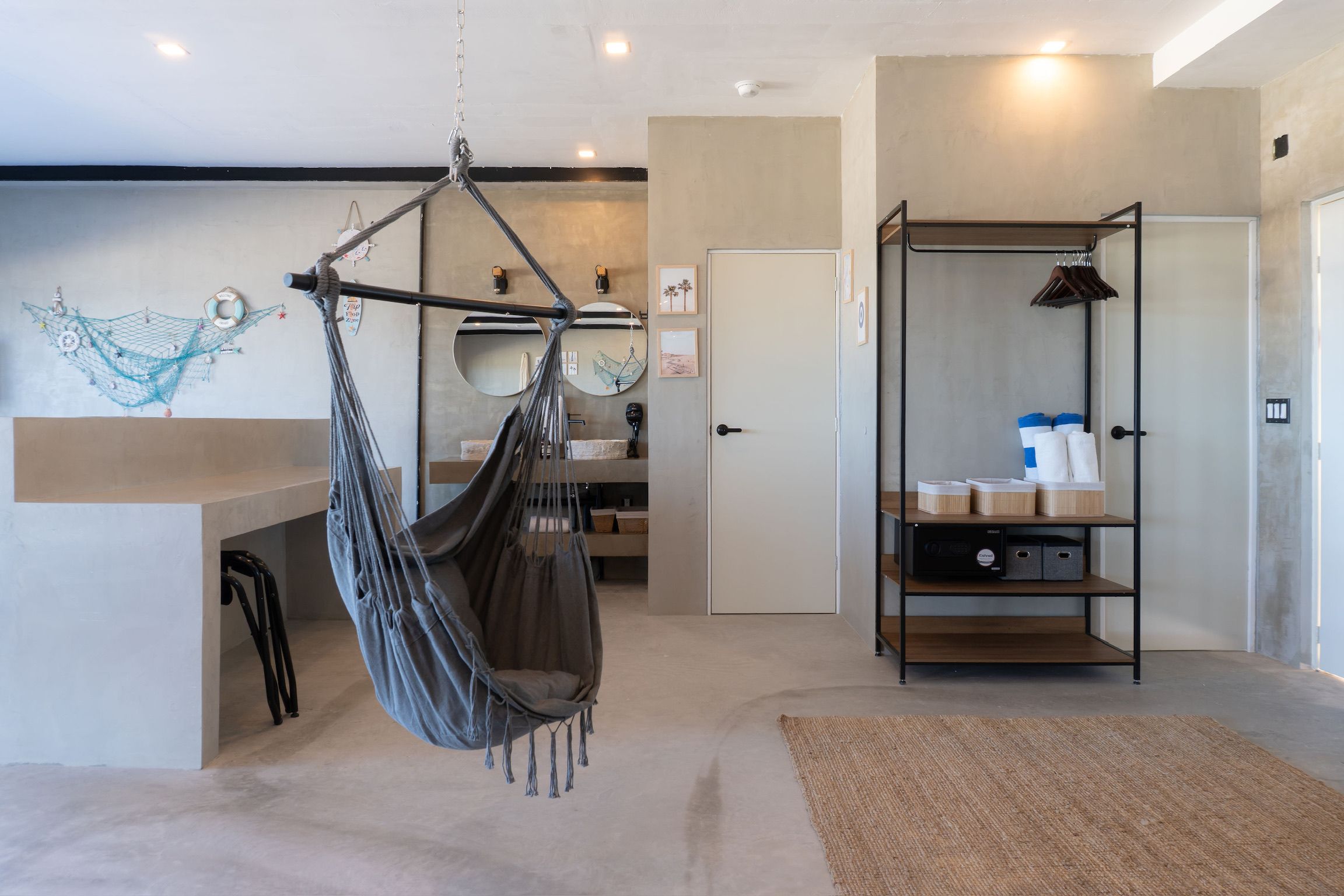 A room with a hanging chair, a wooden shelf with storage boxes, a door, and a wall with decorative items.
