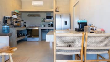 A modern kitchen with a central island, built-in appliances, and a dining area with wicker chairs.