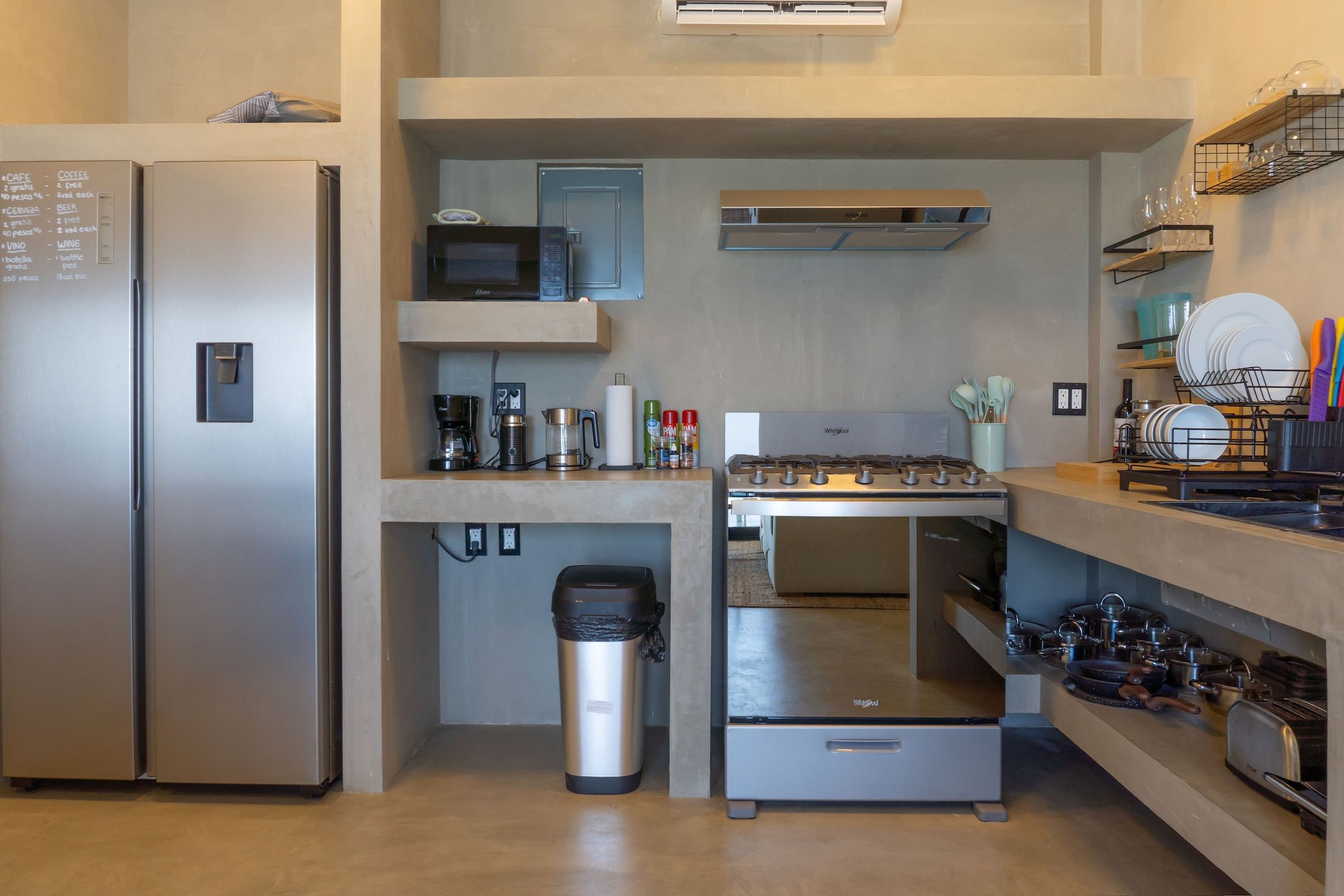A compact kitchen with a refrigerator, microwave, stove, and various utensils.