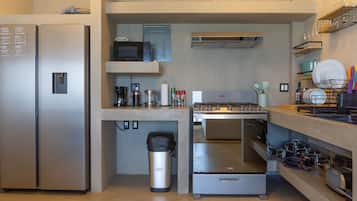 A compact kitchen with a refrigerator, microwave, stove, and various utensils.