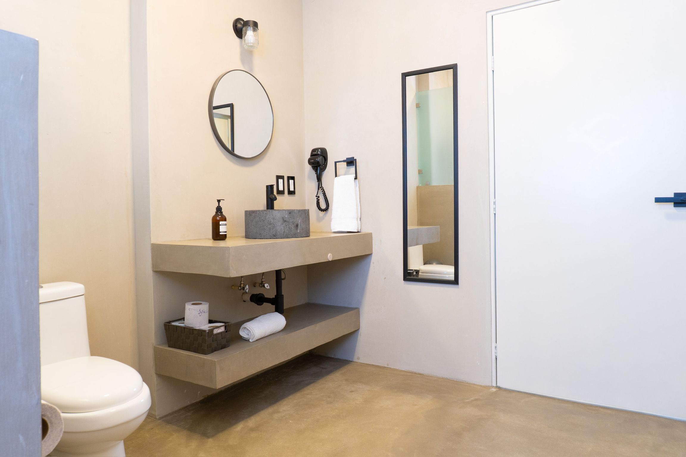 Une salle de bain comprenant des toilettes, un lavabo avec un miroir, un téléphone et un porte-serviettes.