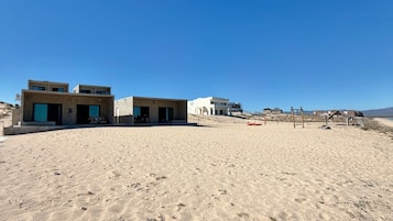A sandy beach with modern buildings and a clear blue sky.
