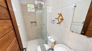 Casa de banho com sanita, lavatório, chuveiro e espelho.
