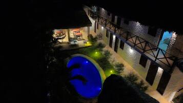 Uma área de piscina com piscina azul, assentos externos e uma estrutura de ponte.