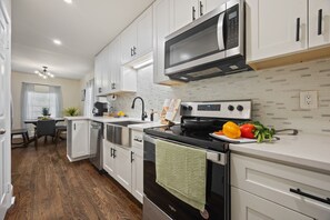 A modern kitchen with white cabinetry, a stainless steel microwave, and a stove. - 3BR ATL near Beltline & Downtown, Fenced Yard + Free Parking (Atlanta)