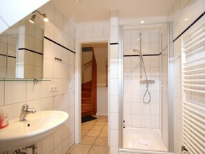 A bathroom with a white sink, a glass shower enclosure, and a visible staircase leading to another room. - Rungholtstrasse 6a, Holiday Apartment 3 (Wyk auf Foehr)