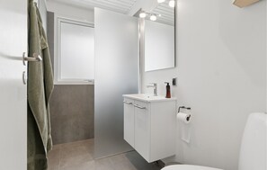 A modern bathroom with a white sink, mirror, and toilet. - 4 bedroom lovely home in Thisted (Thisted)
