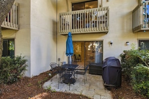 A patio with a table and chairs, a barbecue grill, and a covered seating area. - South Forest Beach Villa Walk to Beach and Coligny (Hilton Head Island)