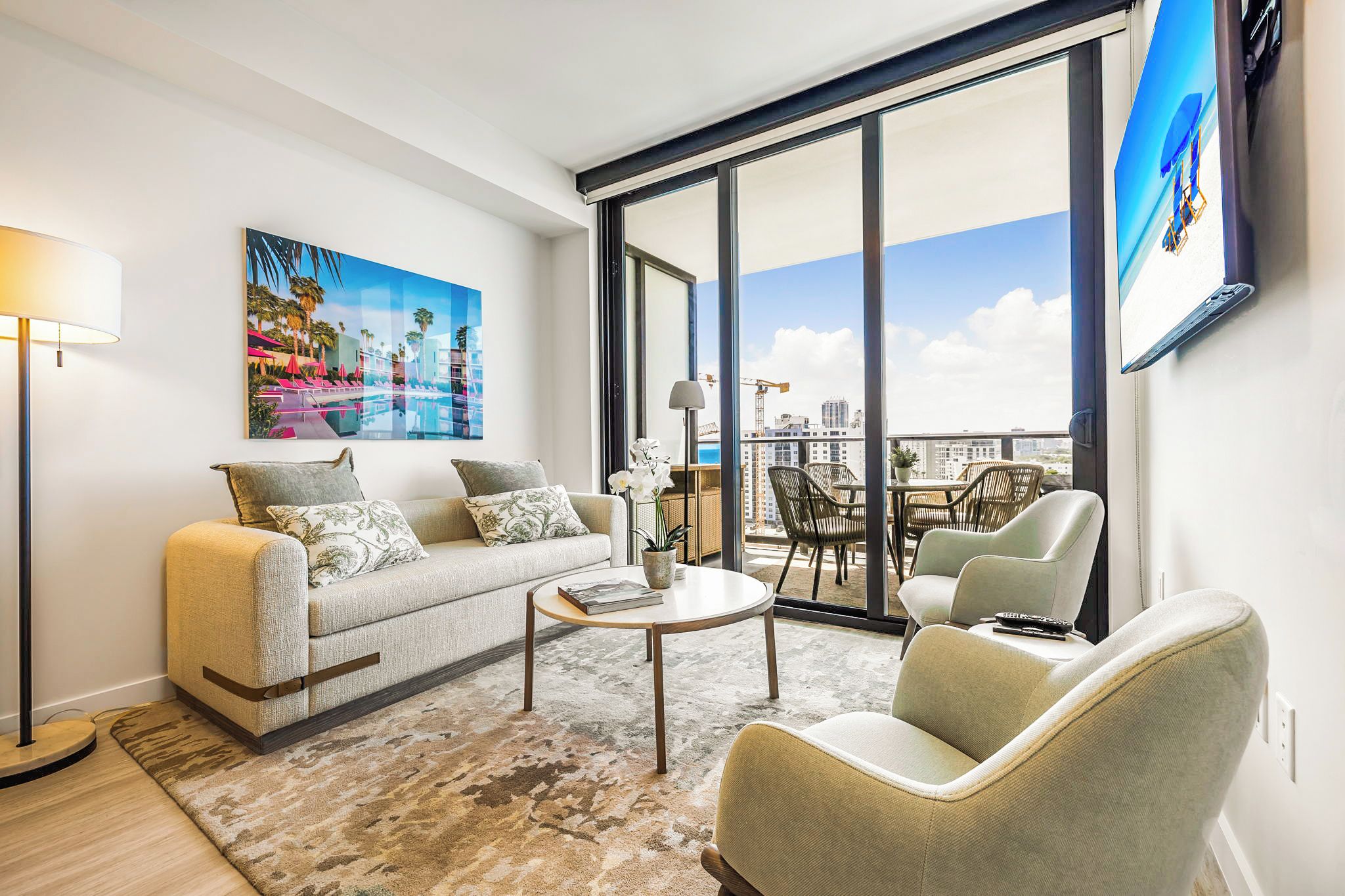 A modern living room with a sofa, armchairs, a coffee table, and a large window with a city view.