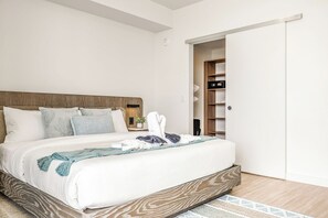 A modern bedroom with a wooden headboard, a large bed with white bedding, a blue throw blanket, and a white towel. - Miami Beach Retreat Steps from the Shore (Miami Beach)