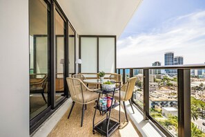 Un balcón con una mesa, sillas, una planta y vistas de la ciudad.
