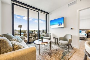 Una sala de estar moderna con un ventanal grande, un televisor de pantalla plana y vista a la playa.