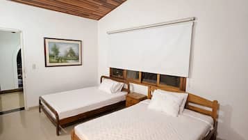 Une pièce avec deux lits en bois, un mur blanc, un tableau encadré et un plafond blanc.