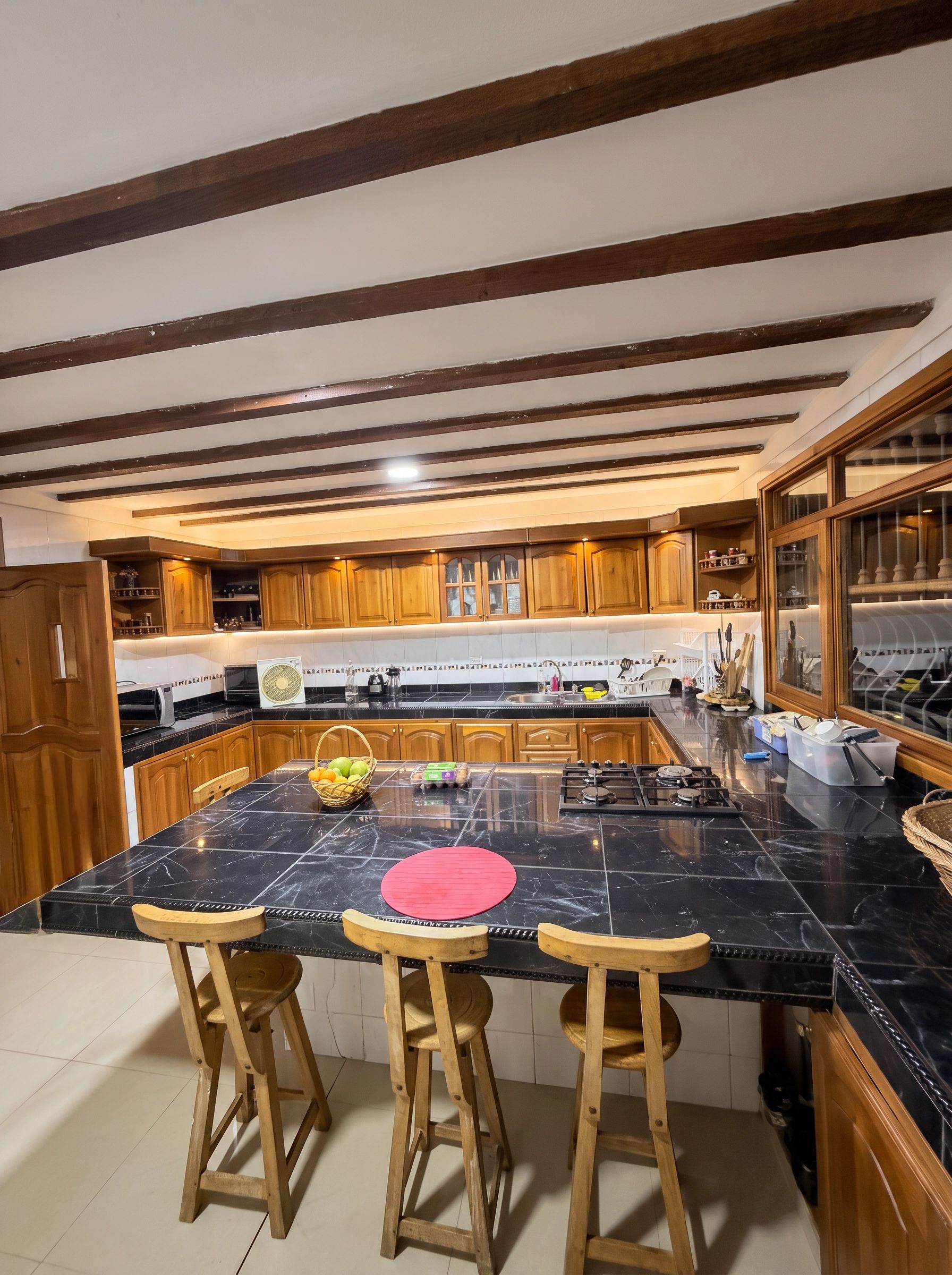 A kitchen with a large island, wooden bar stools, and a gas stove.