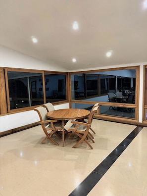Un comedor moderno con una mesa de madera redonda y sillas, ventanas amplias y un suelo pulido.