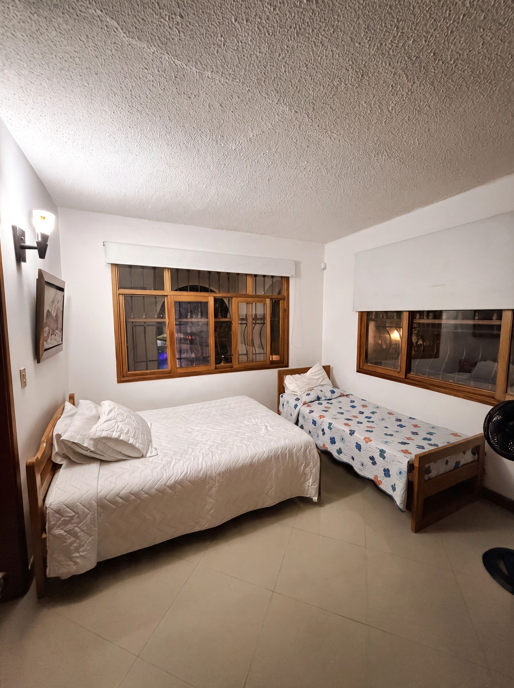 Un dormitorio con dos camas, una ventana y un ventilador de techo.