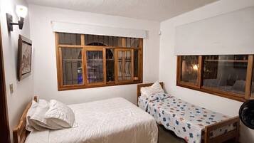 Un dormitorio con dos camas, una ventana y un ventilador de techo.