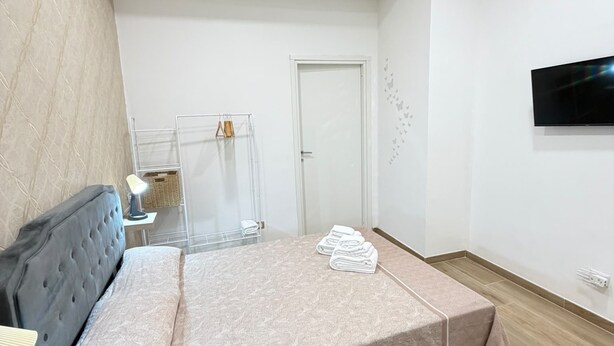 A bedroom with a bed, a desk, a chair, a TV, and a door. - B&B Int'O'Vico – Deluxe Double Room 6 with Wi-Fi and Air Conditioning (Napoli)