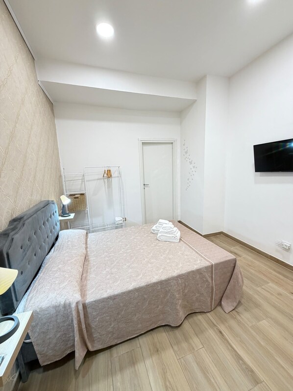 A bedroom with a bed, a desk, a chair, a TV, and a door. - B&B Int'O'Vico – Deluxe Double Room 6 with Wi-Fi and Air Conditioning (Napoli)