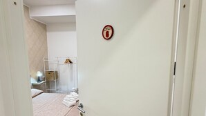 A hotel room with a bed, a towel rack, and a door with a fire safety sign. - B&B Int'O'Vico – Deluxe Double Room 6 with Wi-Fi and Air Conditioning (Napoli)