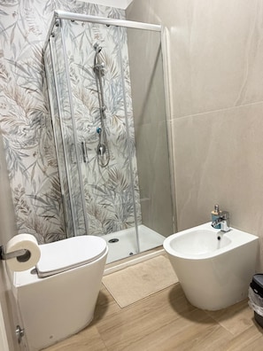 Un baño con inodoro, bidé y cabina de ducha.