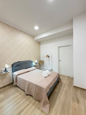 A modern bedroom with a bed, bedside lamps, a wardrobe, and a door. - B&B Int'O'Vico – Deluxe Double Room 6 with Wi-Fi and Air Conditioning (Napoli)