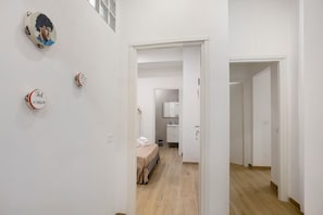 Passadís amb un llit i un bany visibles a través d'una porta oberta.