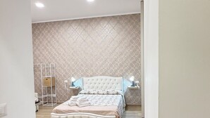 A bedroom with a large bed, two bedside lamps, a wall-mounted shelf, and a patterned wall. - B&B Int'O'Vico – Premium Double Room 29 with Balcony, Wi-Fi & Air Conditioning (Napoli)