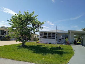 Ein Wohnhaus mit gepflegtem Rasen, einem Baum und blauem Himmel.