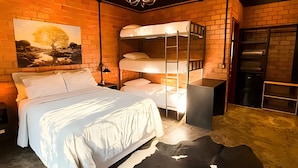A room with a bunk bed, a single bed, a chandelier, a painting, and a brick wall. - ASA Quinta da Esmeralda Bar Pool Cabins (Itajai)