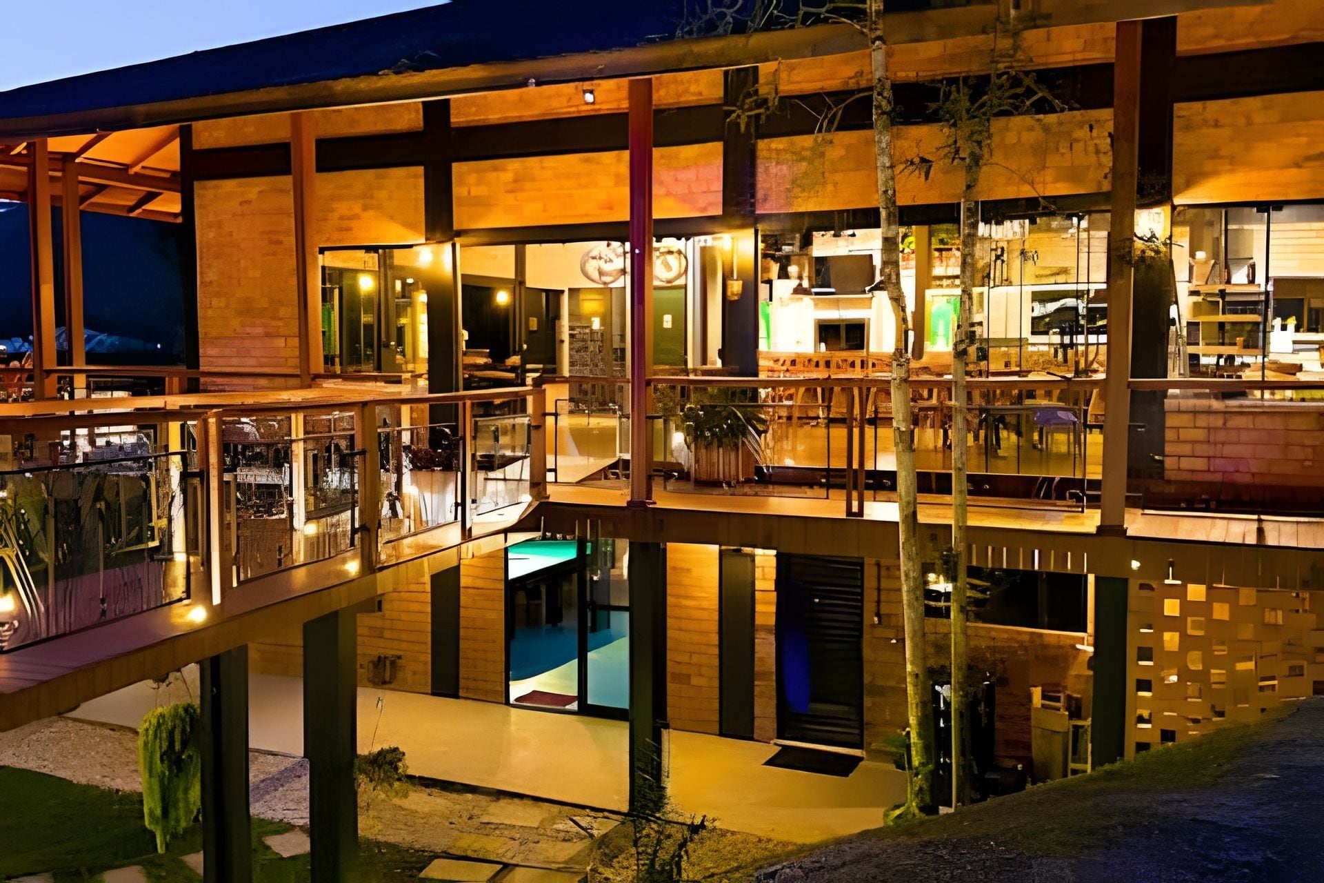 A multi-level modern building with glass balconies, a pool, and a bar area.