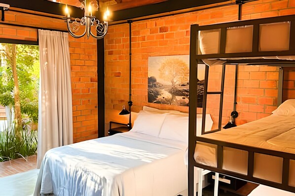 A room with a brick wall, a bed with white bedding, a painting, and a chandelier. - ASA Quinta da Esmeralda Bar Pool Cabins (Itajai)